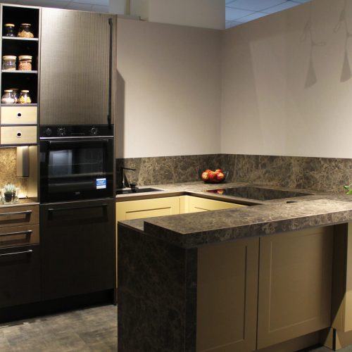 Cucina moderna Life con isola centrale, ante giallo cream, elettrodomestici neri e top in pietra scura.