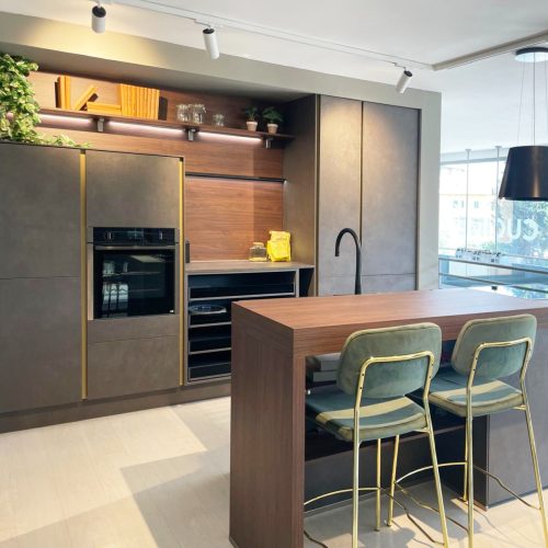 Cucina moderna con isola centrale in legno, sgabelli verde salvia, elettrodomestici integrati e vista panoramica.