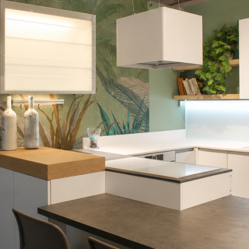 Cucina moderna bianca con isola, pensili sospesi e parete verde con piante decorative