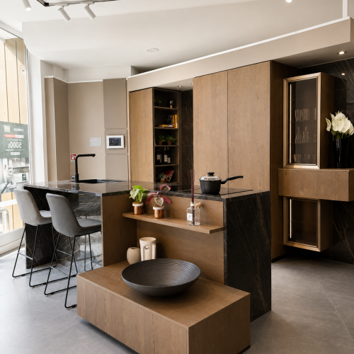 Cucina moderna Life con isola centrale in legno, piani neri e sedie grigie, showroom design