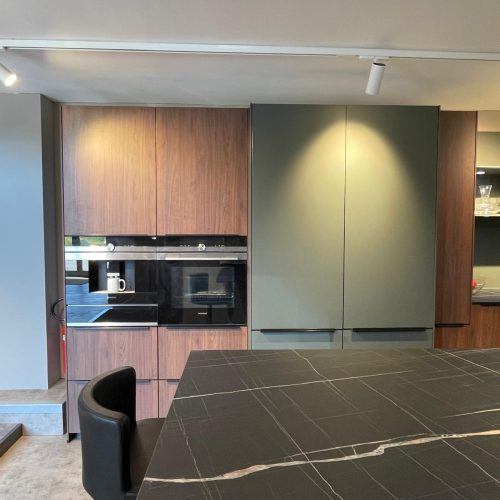 Cucina moderna con tavolo nero in marmo, cappe integrate e frigorifero inox, showroom Life Cucine