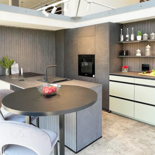 Cucina moderna Life con isola circolare, penisola bianca, ripiani in legno e appliance nere integrate.